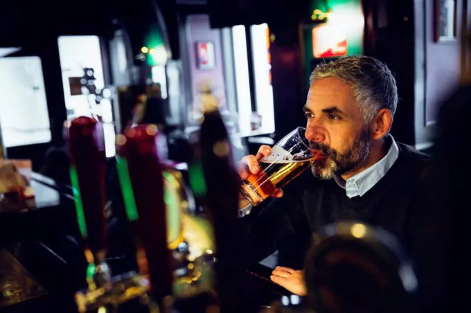 Man sitting at counter of a pub drinking beer