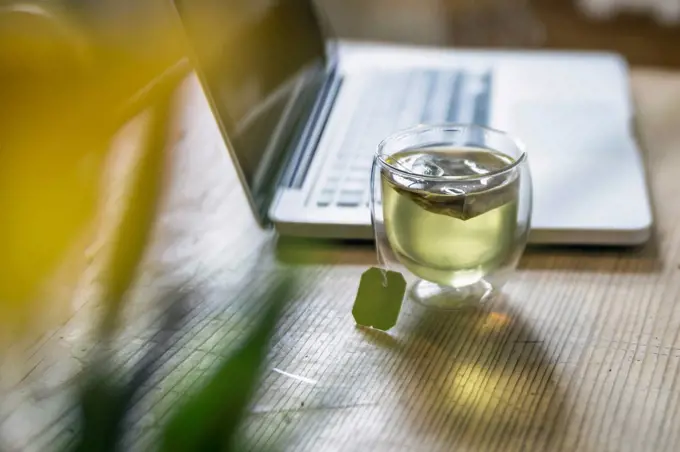 Glass of green tea beside laptop