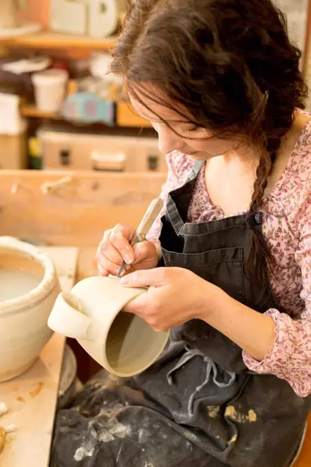 Potter in workshop working on earthenware jug