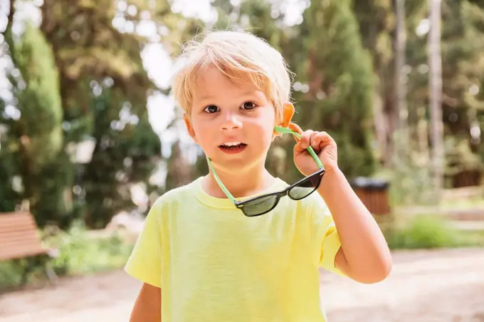 Spain, Mallorca, portrait of blond little boy holding sunglasses