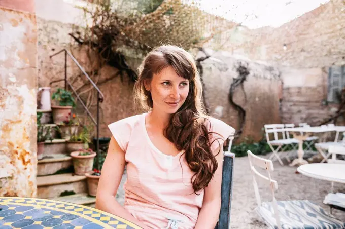 Spain, Mallorca, Arta, portrait of woman sitting at courtyard of a cafe