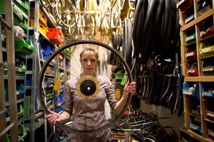 Young woman in a bicycle repair shop holding tire