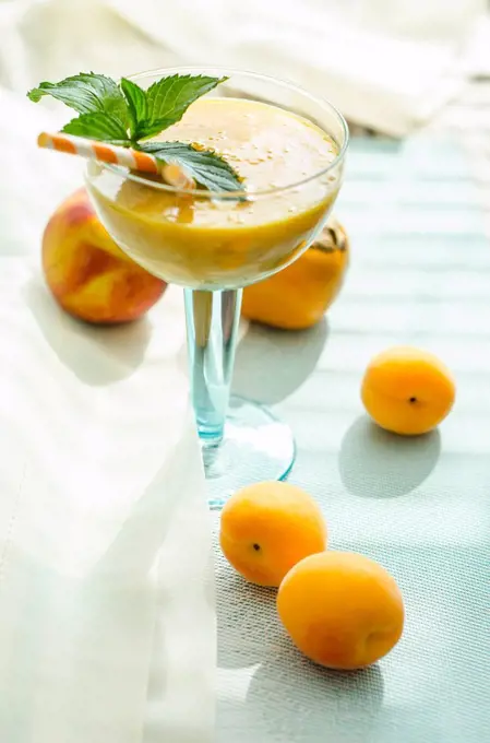 Peach apricot smoothie in glass, drinking straws