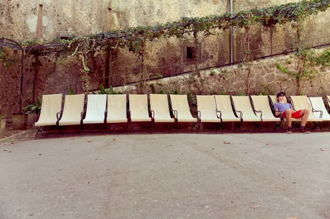 Spain, Mallorca, Young boy relaxing in a canvas chair, row of chairs