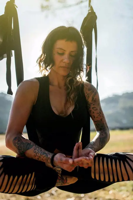 Woman practicing aerial yoga outdoors