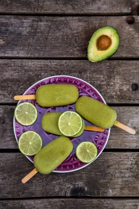 Avocado ice lollies and slices of lime on plate