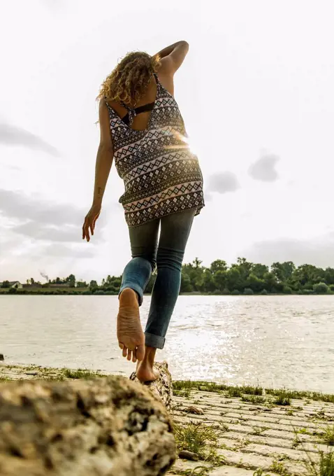 Young woman balancing on log by the riverside