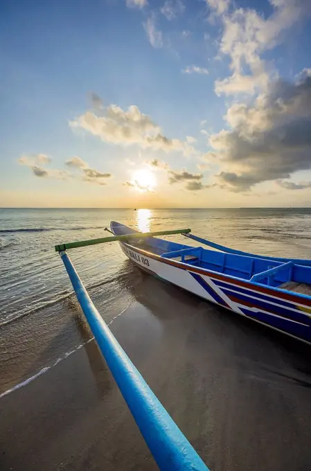 Indonesia, Bali, Jimbaran, Traditional fishing boat on the beach at sunset