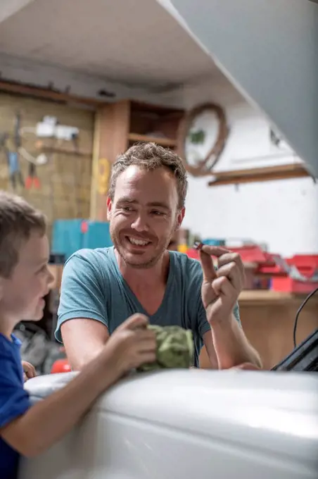 Son helping father in home garage working on car