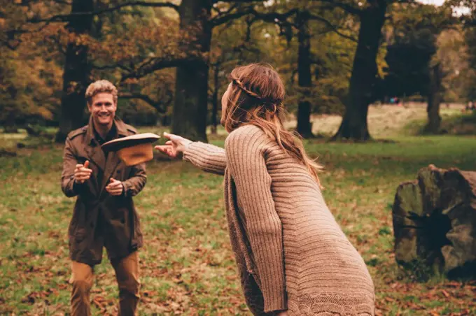 Young couple playing with a hat in an autumnal park