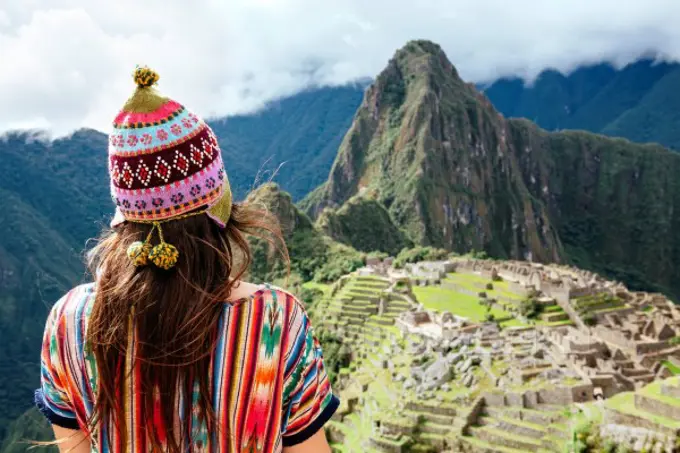 Peru, Machu Picchu region, Female traveler looking at Machu Picchu citadel and Huayna mountain