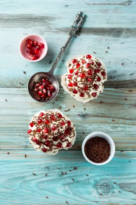 Cupcake with vanilla topping, pomegranate seeds and chocolate granules