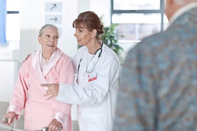 Doctor leading elderly patient on hospital floor