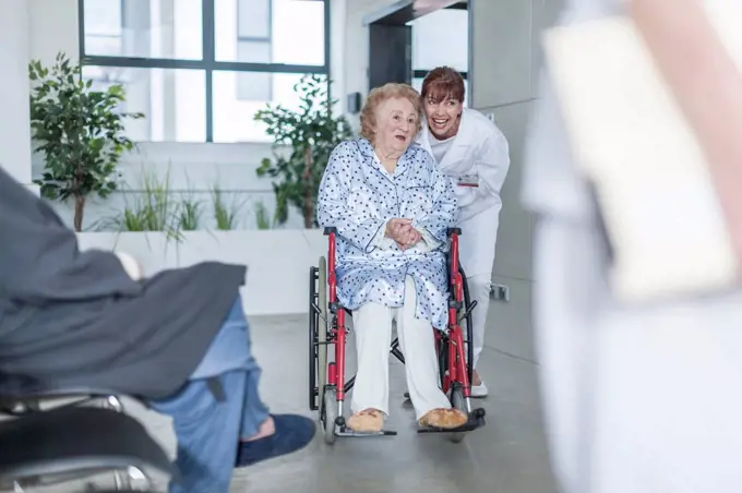 Doctor with elderly patient in wheelchair on hospital floor