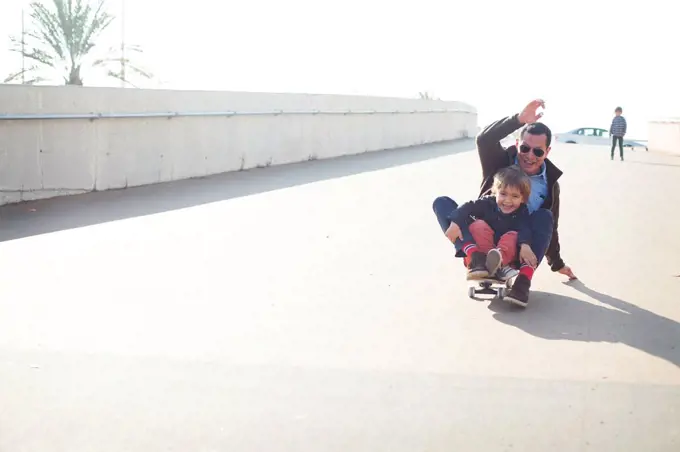 Spain, Catalonia, Barcelona, Uncle and kids doing skate board