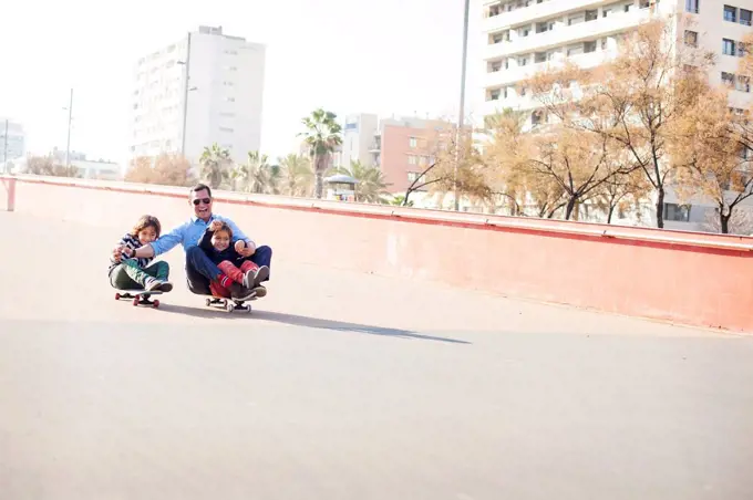 Spain, Catalonia, Barcelona, Uncle and kids doing skate board