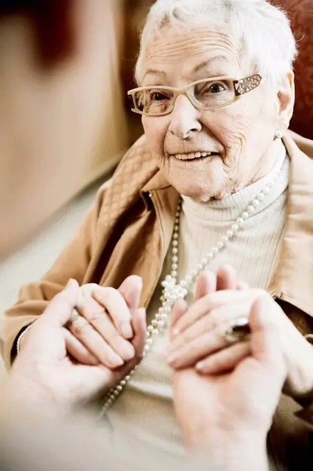 Portrait of senior woman with Alzheimer's disease holding hands of her adult daughter