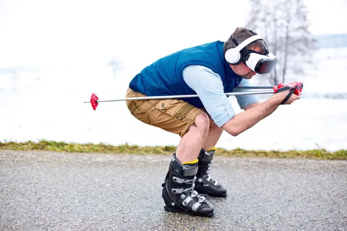 Man wearing Virtual Reality Glasses on winter road pretending to skiing