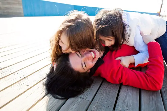 Mother and her two daughters playing on a deck