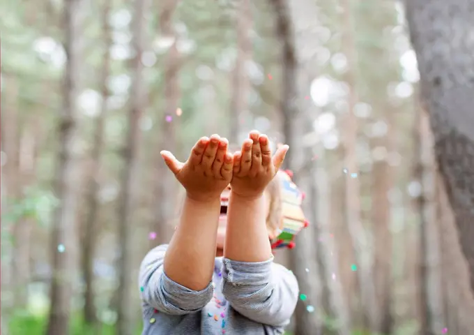 Little boy catching confetti in the woods