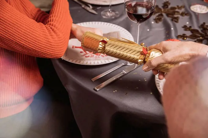 Two female hands pulling at ends of a Christmas cracker