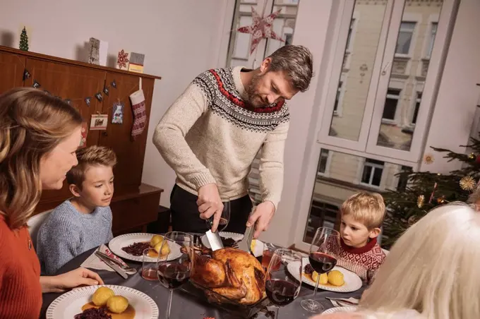 Father cutting the turkey during Christmas dinner