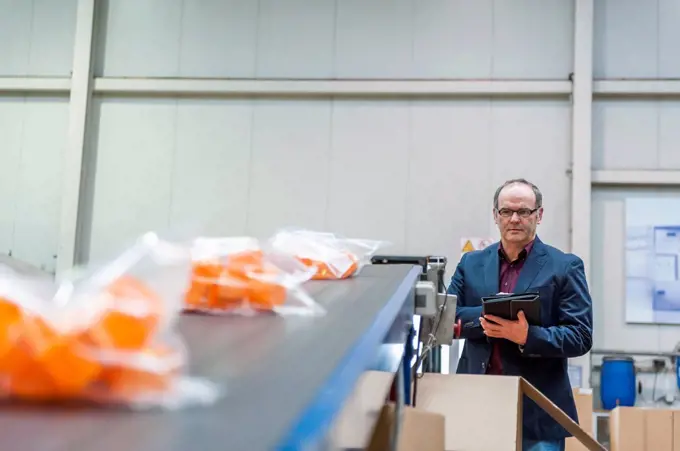 Manager checking packaging of goods in plastics factory