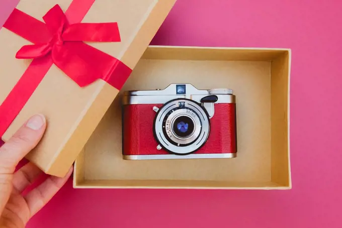 Woman's hand opening a gift box with a beautiful analog camera inside