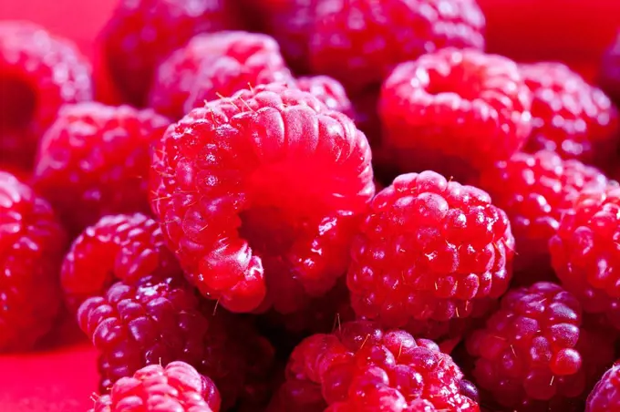 Raspberries on red background, close up