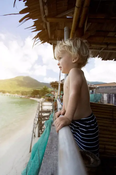 Thailand, toddler in a in beach hut looking at distance