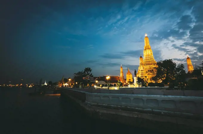 Thailand, Bangkok, Wat Arun at twilight with Chao Praya River in the foreground