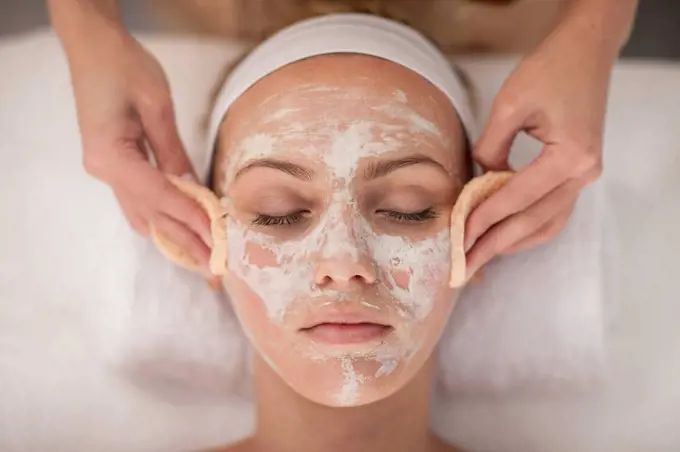 Young woman in spa receiving facial mask