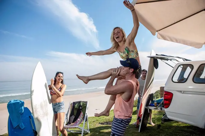 Man lifting up excited woman at the coast