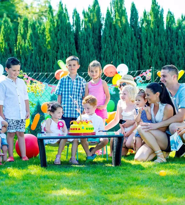 Children celebrating birthday party with friends and family in the garden