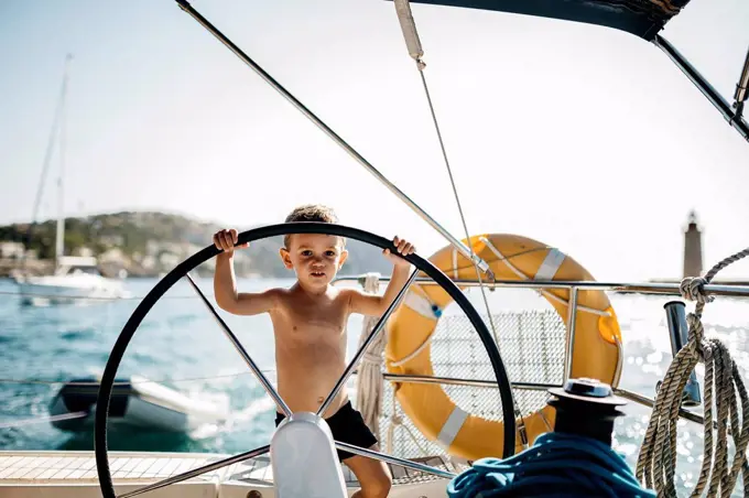 Little boy at the helm of a sailing boat