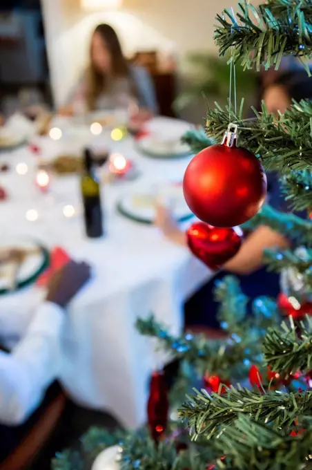 Christmas tree bauble and friends having Christmas dinner