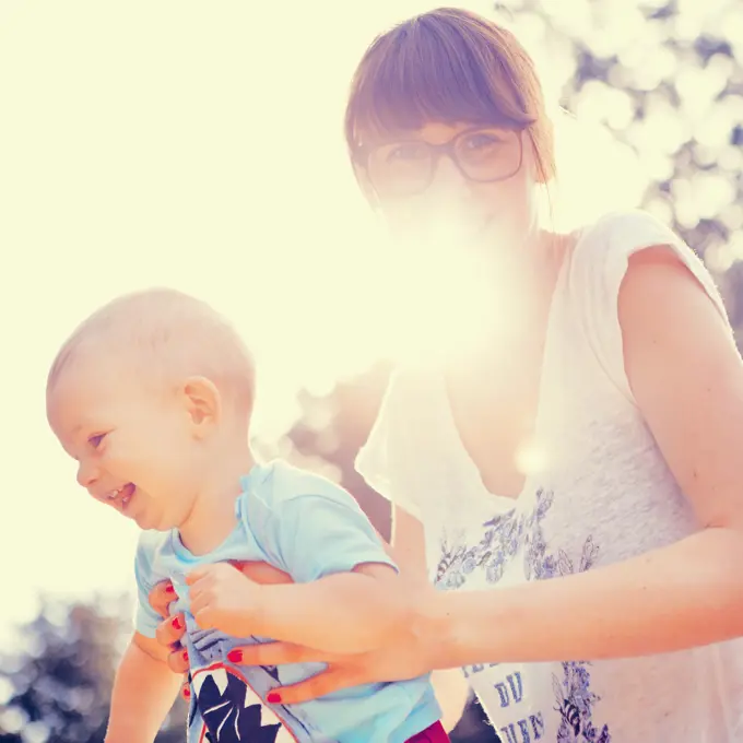 Mother holding happy baby outside