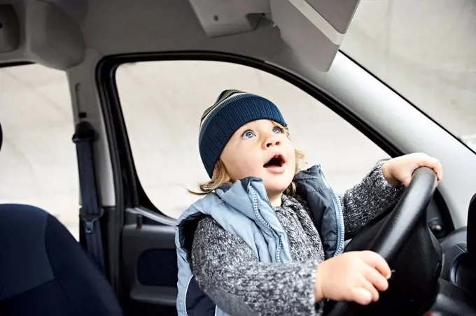 Little boy sitting at steering wheel of car