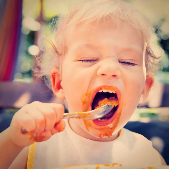 Little boy eating with his own spoon