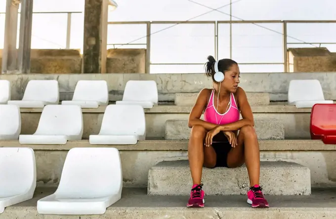 Female athlete taking a break, listening to music