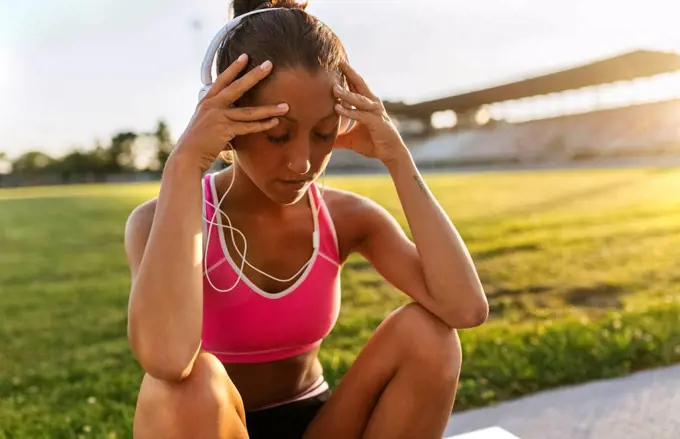 Female athlete taking a break, listening to music