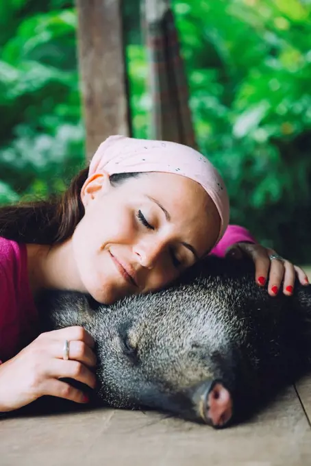 Peru, Woman cuddling domesticated peccary