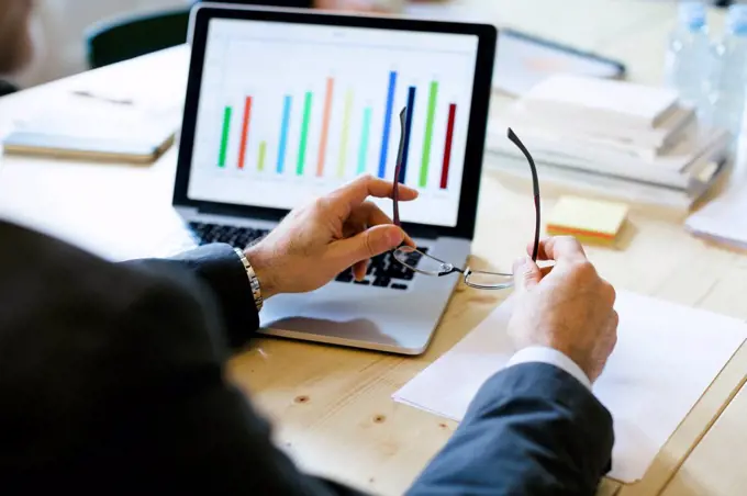 Businessman studying bar chart on laptop