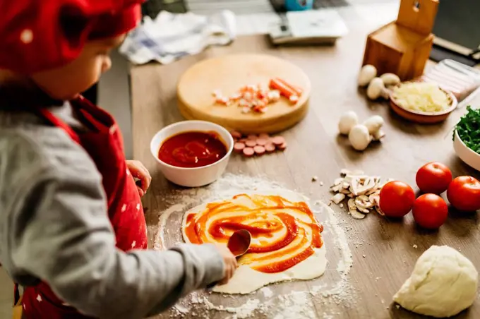 Little boy preparing pizza at home