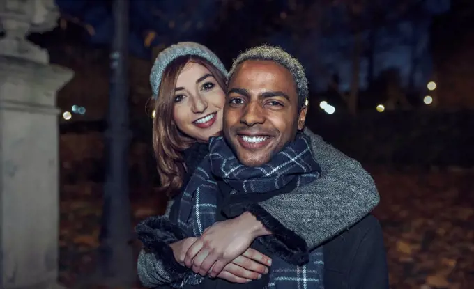 Portrait of happy young couple in front of park