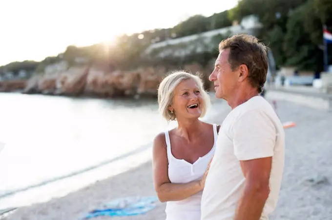 Senior couple relaxing on the beach at evening twilight