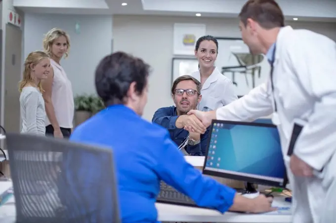 Patient in wheelchair greeting doctor at the reception