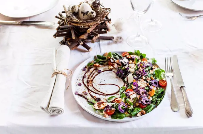 Colourful salad plate with smoked salmon, Crema di Balsamico and hazelnut oil on laid table