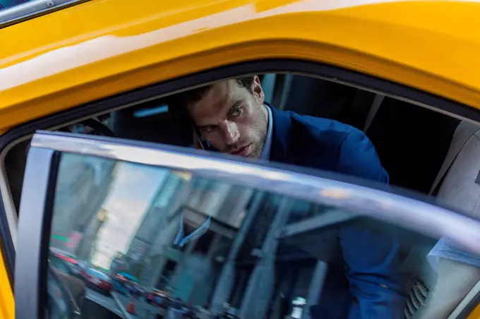 Businessman sitting in taxi, using smart phone