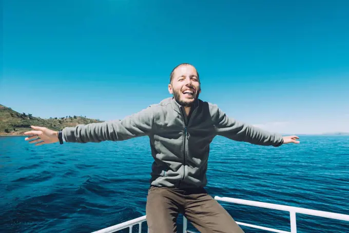 Peru, Titicaca lake, Taquile, happy man with outstretched arms on a boat